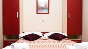 Habitación de hotel con cama, dos almohadas, un cuadro en la pared y un armario rojo.