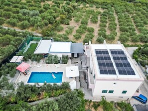 Ein Luftbild eines Wohnhauses mit Swimmingpool, Solaranlage und Garten.