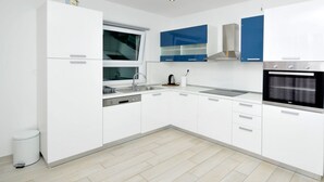 A modern kitchen with white cabinets, a built-in oven, and a window above the sink. - Villa Rimac in Kastel Stafilic mit Garten, Grill by Interhome (Kaštel Novi)