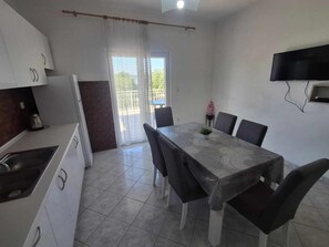 A compact kitchen with a dining table and chairs, a TV mounted on the wall, and a balcony with a view. - Sonnige Wohnung "Bepo" mit Blick auf das Wasser by Interhome (Zadar/Bibinje)