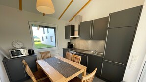 Uma cozinha moderna com mesa de jantar, cadeiras, micro-ondas, fogão e geladeira.