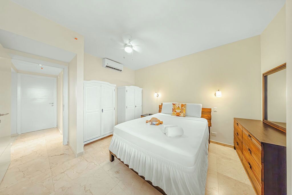 Un dormitorio con cama, cómoda, espejo y aire acondicionado.