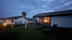 A residential area with houses, a grassy yard, and a patio with chairs. - mit Aussensauna für 2 Personen by Interhome (Burhave)