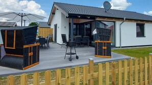 Ett modernt utomhusområde med möbler i rotting, en överbyggd sittplats och en satellantenn på taket.