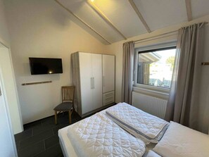 Hotelkamer met een bed, een aan de muur bevestigde televisie, een kast en een raam met gordijnen.