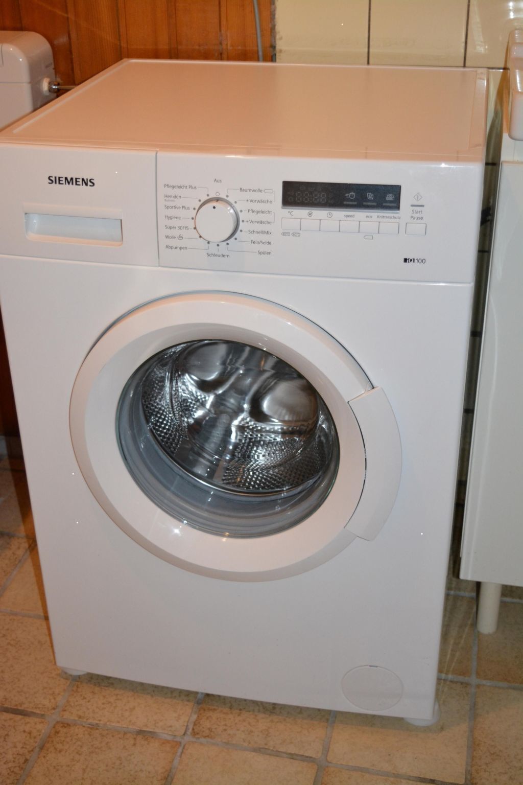 A white Siemens front-loading washing machine with a control panel and a digital display.