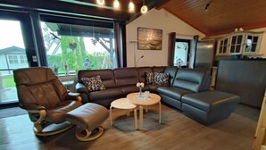 Ein modernes Wohnzimmer mit einem Ledersofa, einem Schaukelstuhl und einem kleinen Couchtisch.