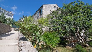 Un bâtiment en pierre doté d’un toit en pente, d’un étroit sentier pavé et d’une végétation luxuriante.