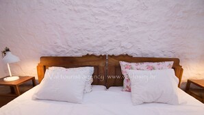 Une chambre à coucher avec une tête de lit en bois, du linge de lit blanc et une table de chevet avec une lampe.