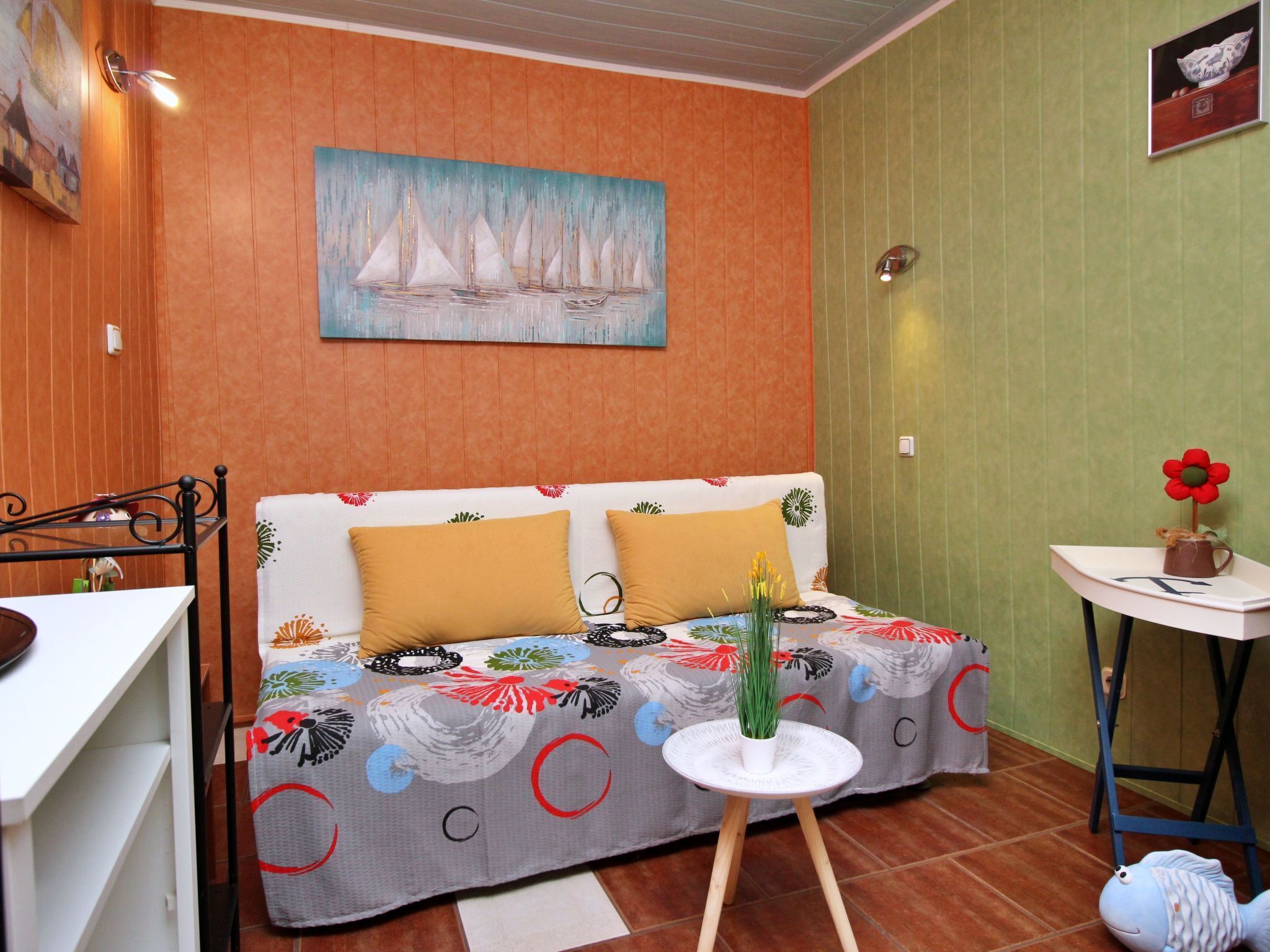 Una habitación acogedora con un sofá, una mesita redonda con una planta y un cuadro en la pared.