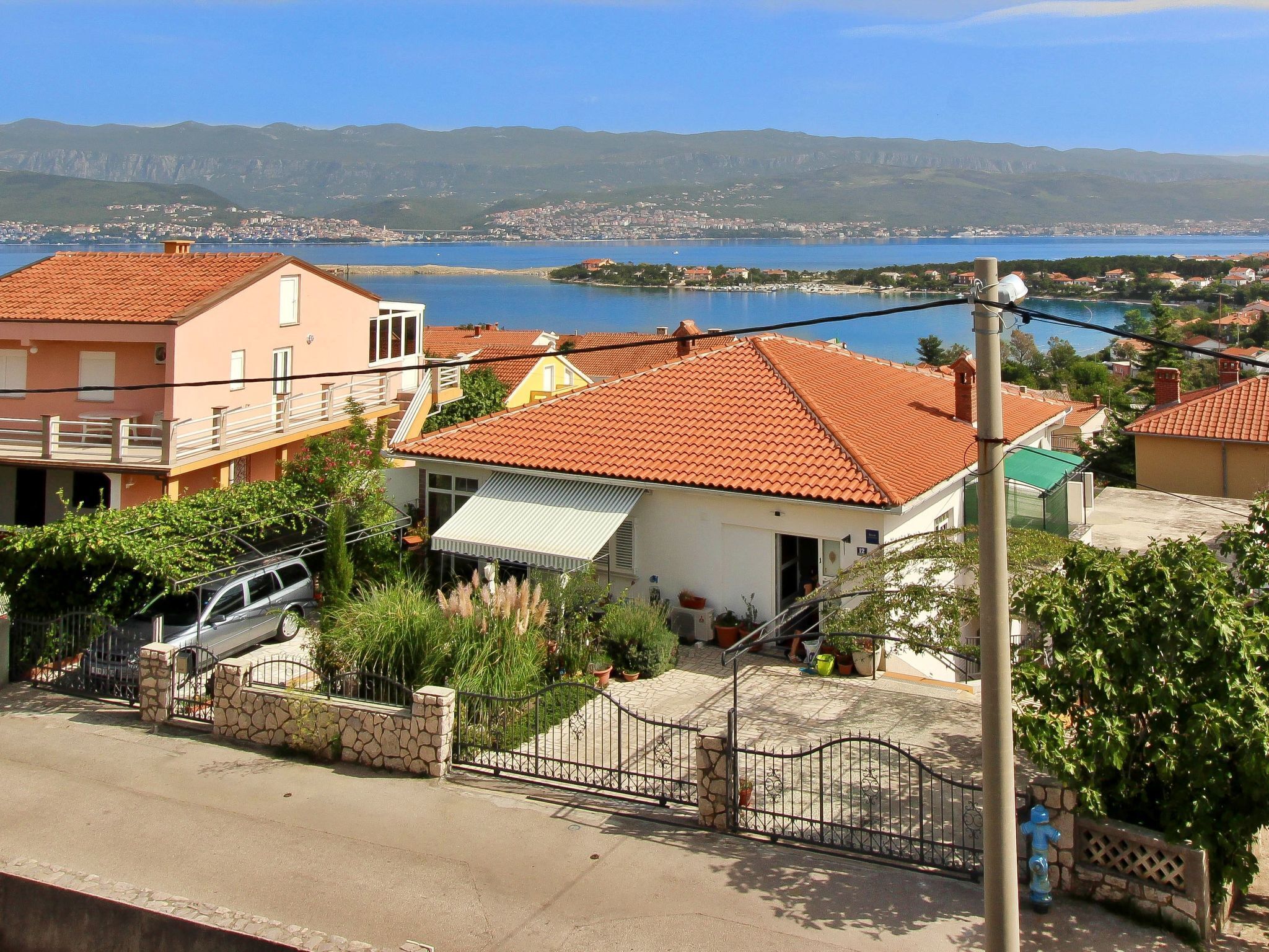 A residential area with houses, a gate, and a view of a lake and mountains.