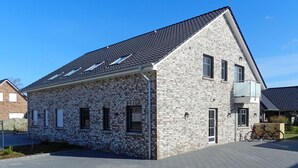 Un edificio moderno a due piani con facciata in pietra, numerose finestre e tetto spiovente.