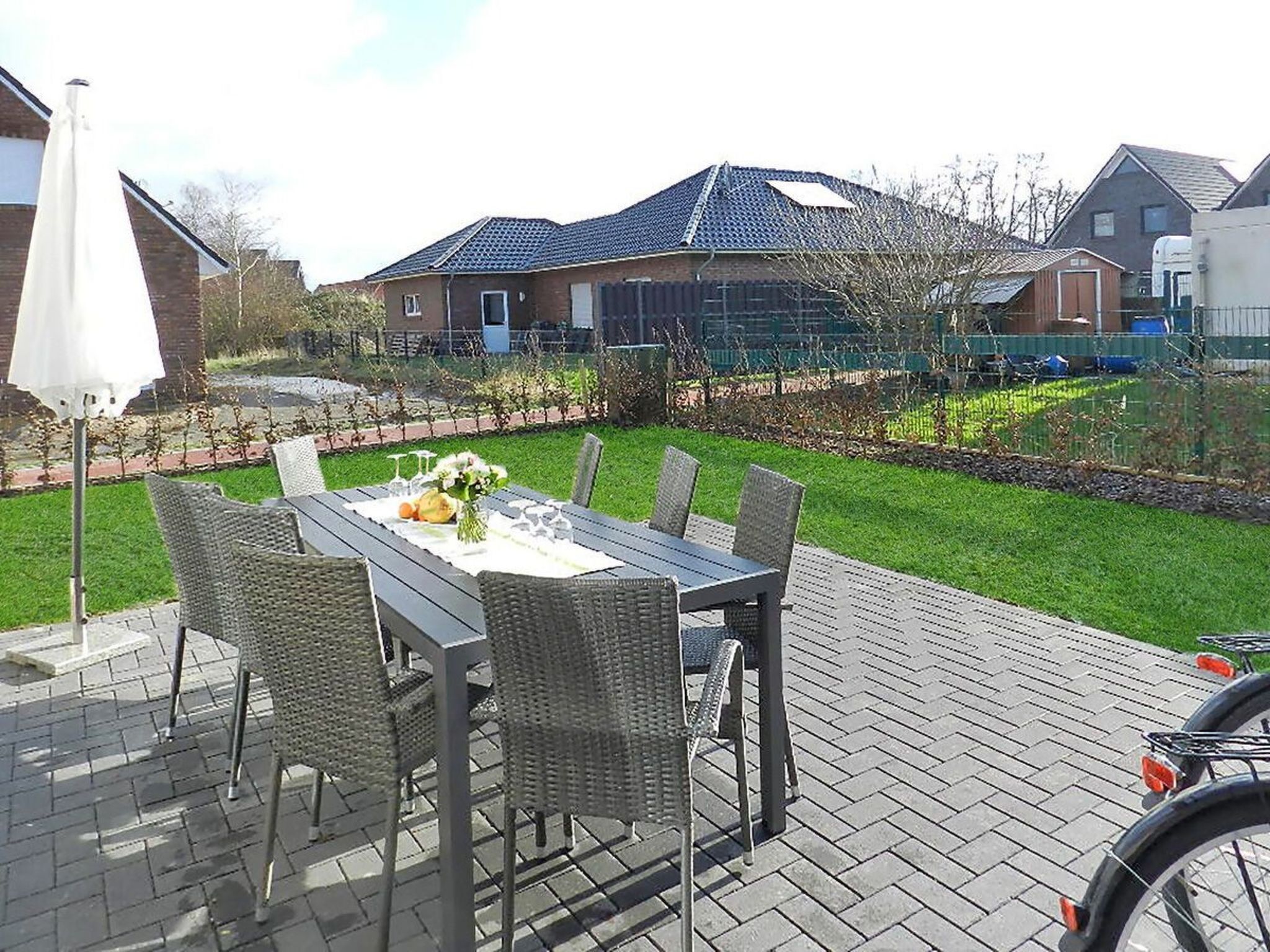 An outdoor patio with a table set for dining, surrounded by wicker chairs.