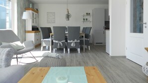 Ett modernt vardagsrum med matplats, kök och utsikt över omgivningen.