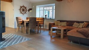 Een knusse woonkamer met een houten eettafel, comfortabele stoelen, een bank en een televisie.