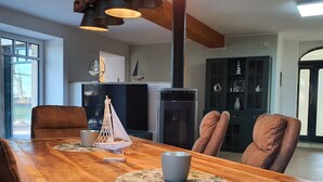 Een eethoek met een houten tafel, twee stoelen, een decoratief zeilschip, en een moderne keuken op de achtergrond.