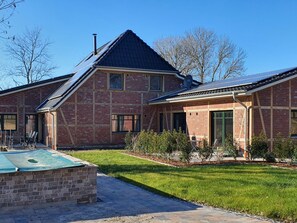 A two-story brick house with a sloped roof, solar panels, and a small patio area. - Friesenhof by Interhome (Burhave)