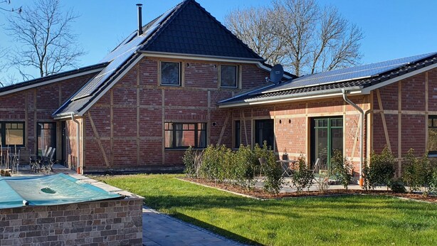 A two-story brick house with a sloped roof, solar panels, and a small patio area. - Friesenhof by Interhome (Burhave)