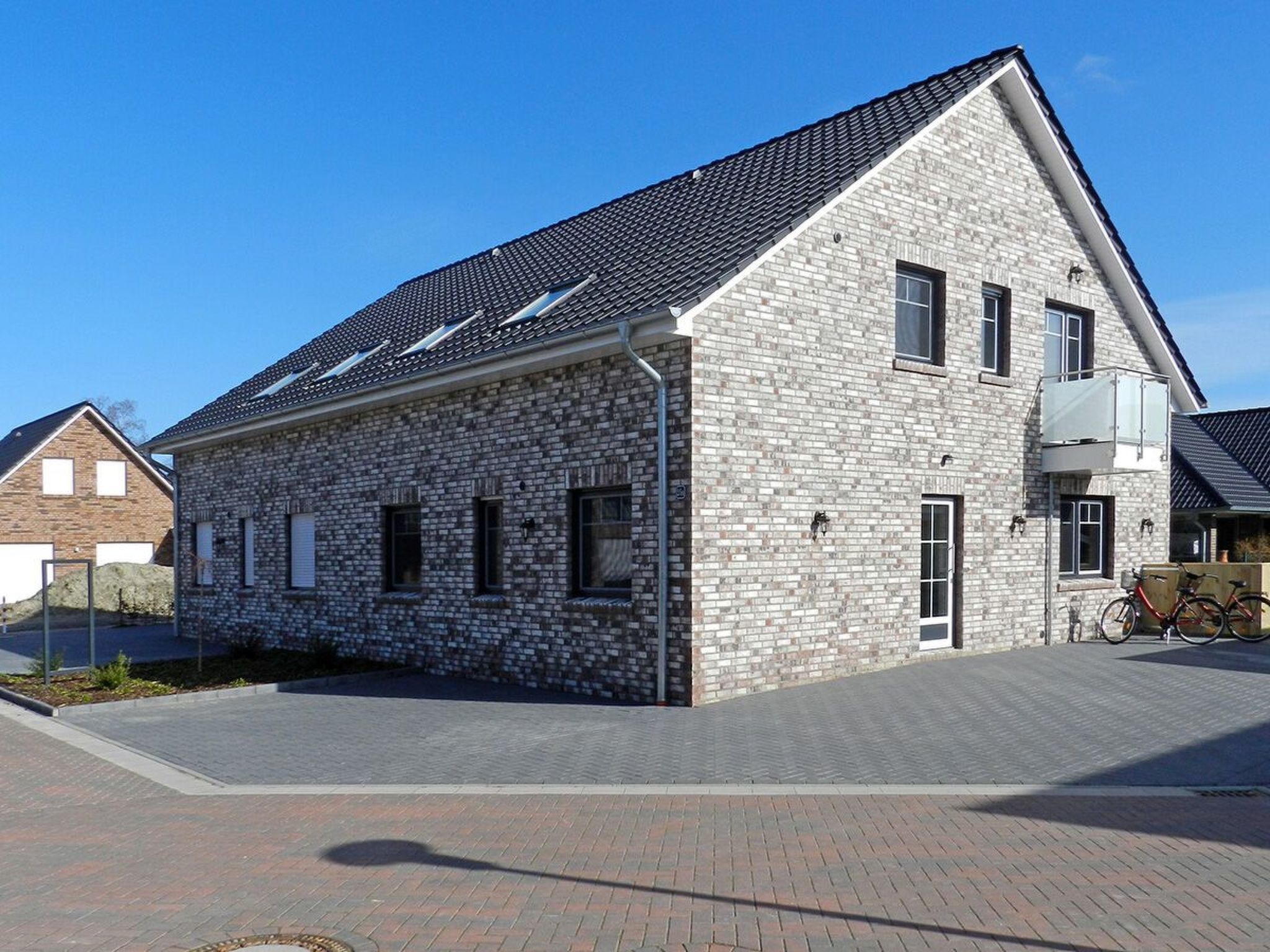 A modern two-story stone building with a sloped roof and multiple windows.