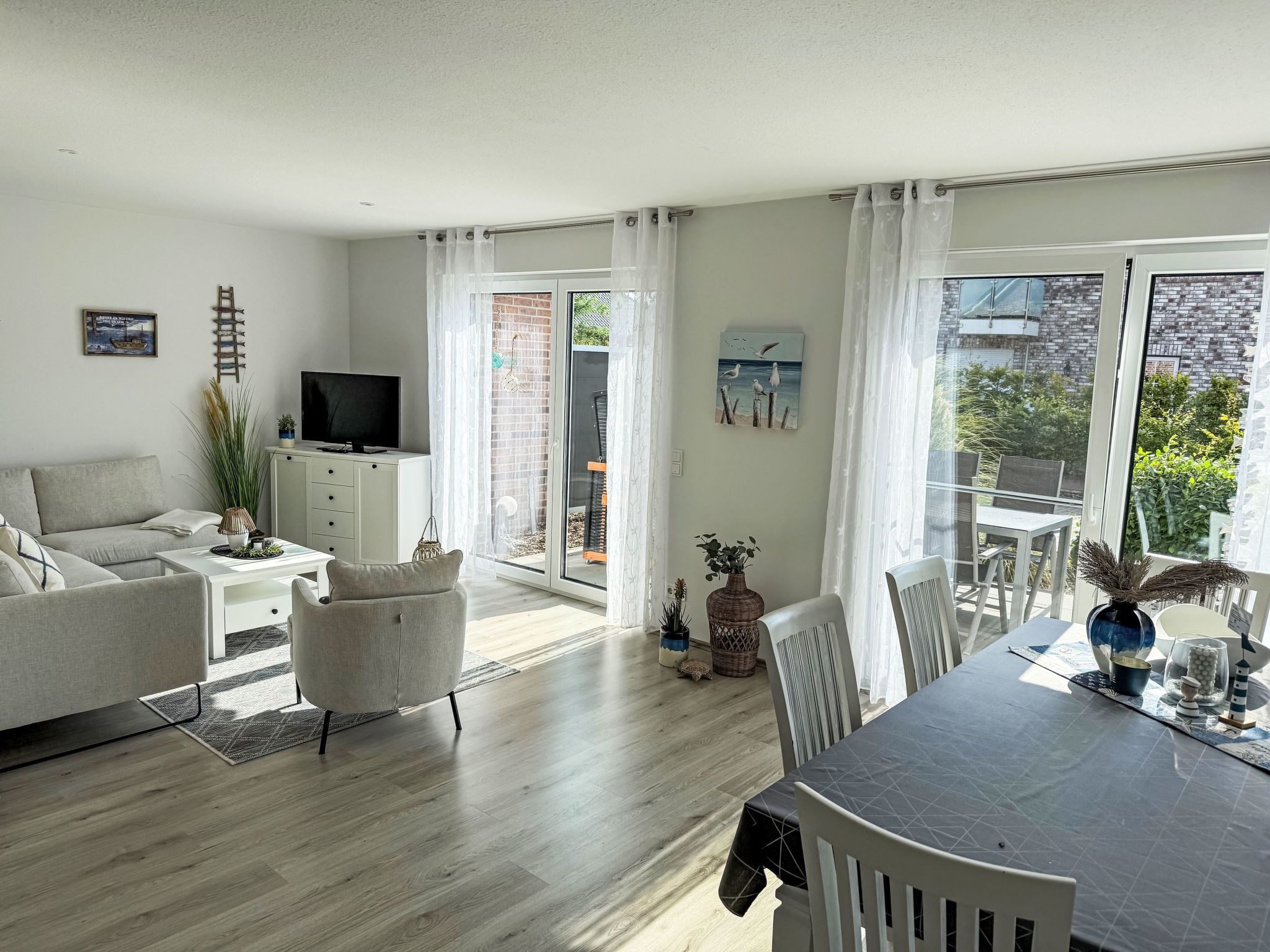A modern living room with a sofa, TV, and dining area with chairs and a table.