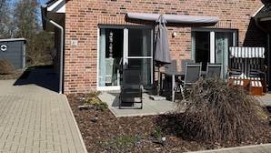 Una casa de ladrillo de dos pisos con un patio que cuenta con mobiliario exterior y una zona de estar cubierta.