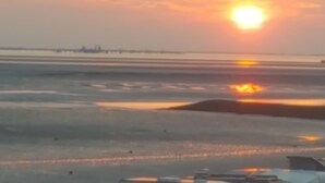 A beach scene with a sunset, calm water, and a distant shoreline. - Ferienhuus Tossens by Interhome (Burhave)