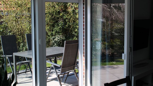 Ein Zimmer mit einer Schiebetür und Zugang zu einer Außenpatio-Terrasse, inklusive Tisch und Stühlen.