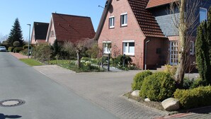 Eine Wohnstraße mit Häusern, deren Fassaden aus Ziegel bestehen und rote Ziegeldeckung haben.