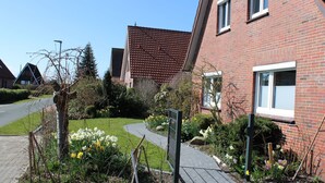 Ein Wohngebiet mit einem Ziegelhaus, einem gepflasterten Weg und einem Garten mit Blumen.