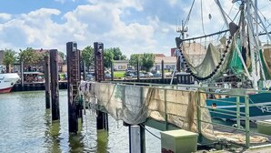 Un quai avec un bateau de pêche, une voie navigable et des bâtiments en arrière-plan.