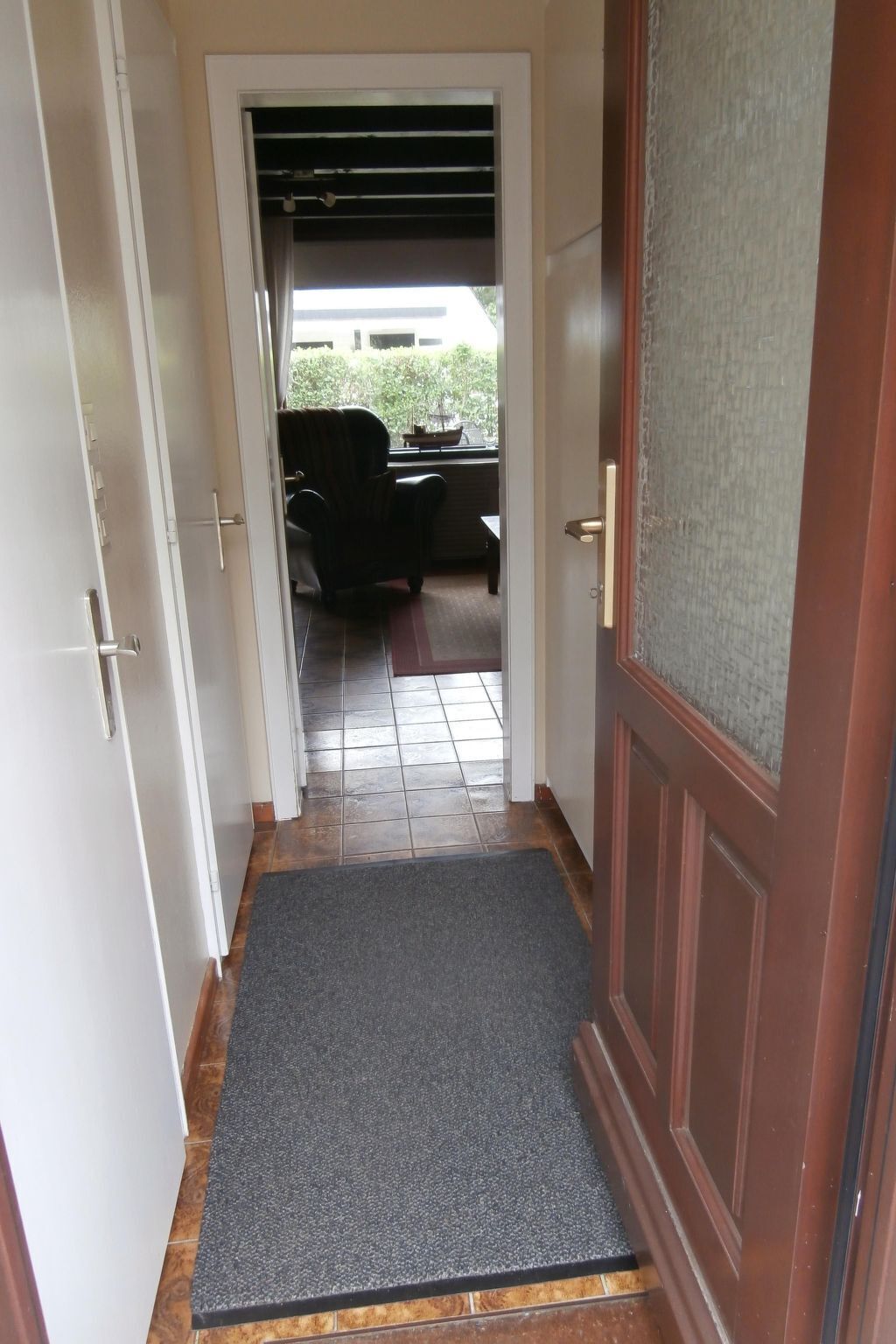 A hallway leading to a patio area with a chair and a table.