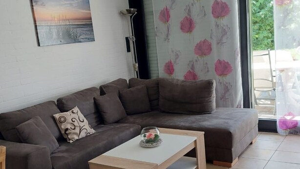 A living room with a sectional sofa, a coffee table, and a painting on the wall. - in Tossens mit Schönem Garten by Interhome (Burhave)