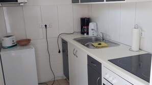 A compact kitchen with white cabinets, a microwave, a toaster, a coffee maker, and a stove. - in Tossens mit Schönem Garten by Interhome (Burhave)