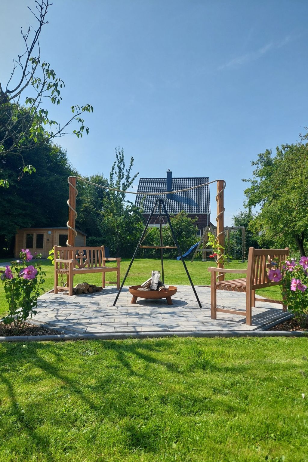 A patio with a swing set, a fire pit, and a bench.