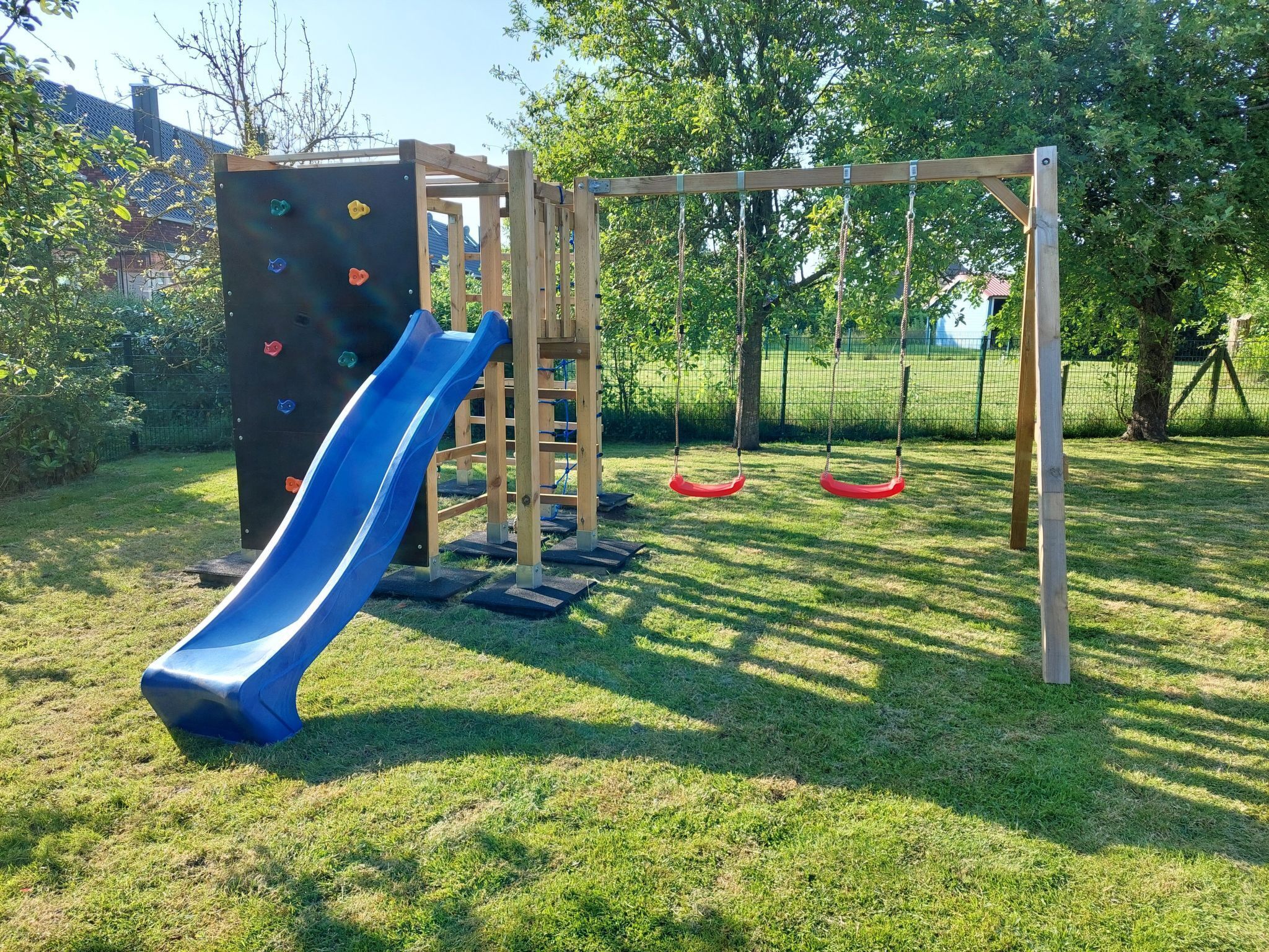 A playground with a slide, climbing wall, and swings.