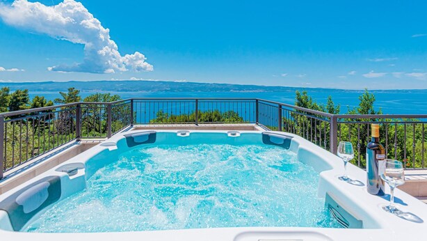 Ein Whirlpool mit freiem Blick auf einen See und Berge im Hintergrund.