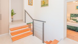 Ein modernes Interieur mit einer Treppe, einem Bett mit grüner Bettwäsche und zwei gerahmten Bildern an der Wand.