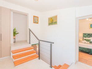 A modern interior with a staircase, a bed with green bedding, and two framed paintings on the wall. - Ferienvilla 'Villa Betelgeuse by Interhome (Omiš)