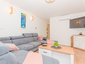 A modern living room with a grey sofa, a wooden coffee table, and a TV mounted on the wall. - Ferienvilla 'Villa Betelgeuse by Interhome (Omiš)