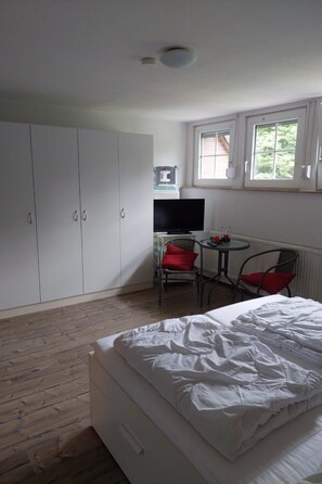 Une chambre à coucher comprenant un lit, une télévision, une petite table avec des chaises et une armoire.