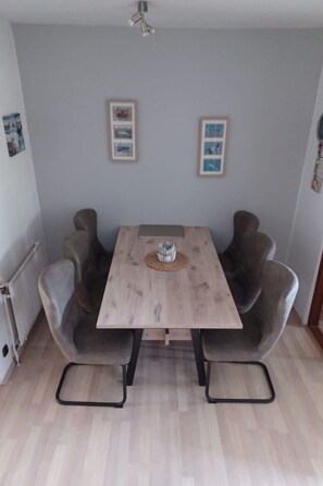 Un coin repas comprenant une table en bois, deux chaises grises à revêtement rembourré et un petit objet décoratif posé sur la table.