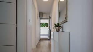 A hallway with a wooden floor, white walls, and a potted plant on a white console. - Große Wohnung in Omis mit Terrasse und Meerblick by Interhome (Omiš)