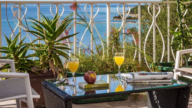 A glass table with drinks and a book, surrounded by plants, with a view of the sea. - Große Wohnung in Omis mit Terrasse und Meerblick by Interhome (Omiš)