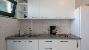 A modern kitchen with white cabinets, a double sink, a coffee maker, and a microwave. - Große Wohnung in Omis mit Terrasse und Meerblick by Interhome (Omiš)
