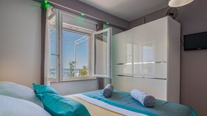 A bedroom with a bed, a wardrobe, a window with curtains, and a television on the wall. - Große Wohnung in Omis mit Terrasse und Meerblick by Interhome (Omiš)