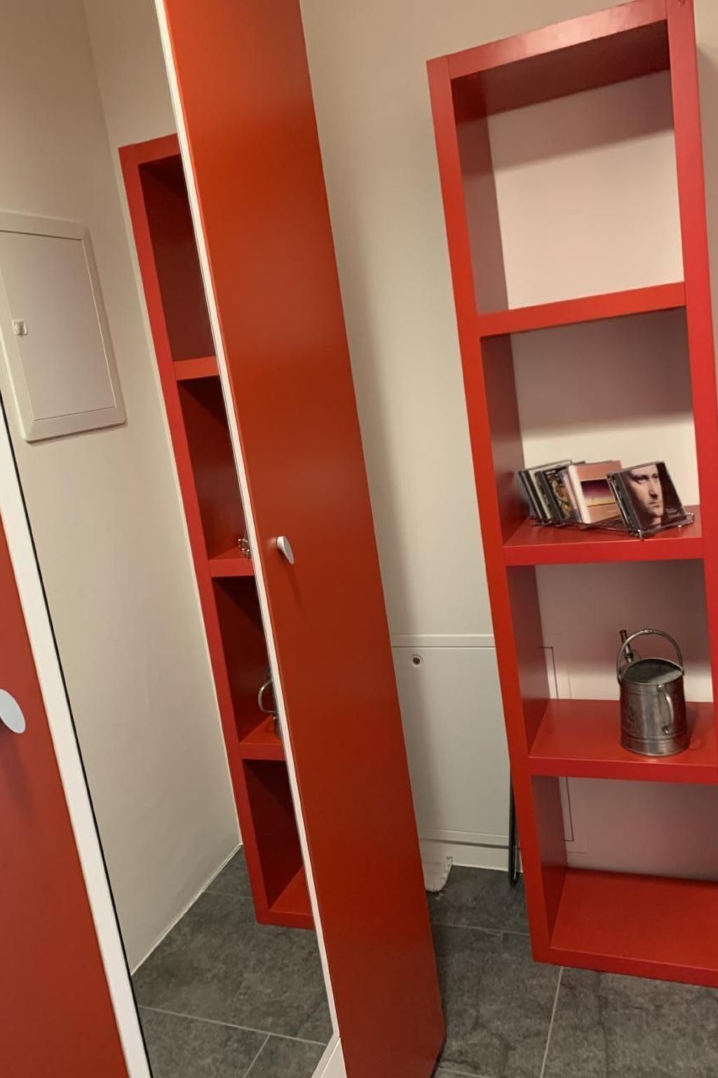 A room with a red bookshelf, a white door, and a small white appliance.