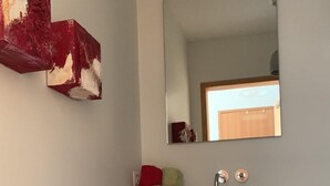 Uma casa de banho com bancada preta, espelho e móvel de armazenamento branco abaixo.