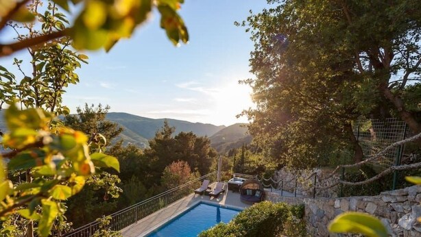 A swimming pool surrounded by stone walls and lush greenery, with a view of distant hills. - Privatwohnung mit Jacuzzi und Schwimmbad by Interhome (Split/Žrnovnica)