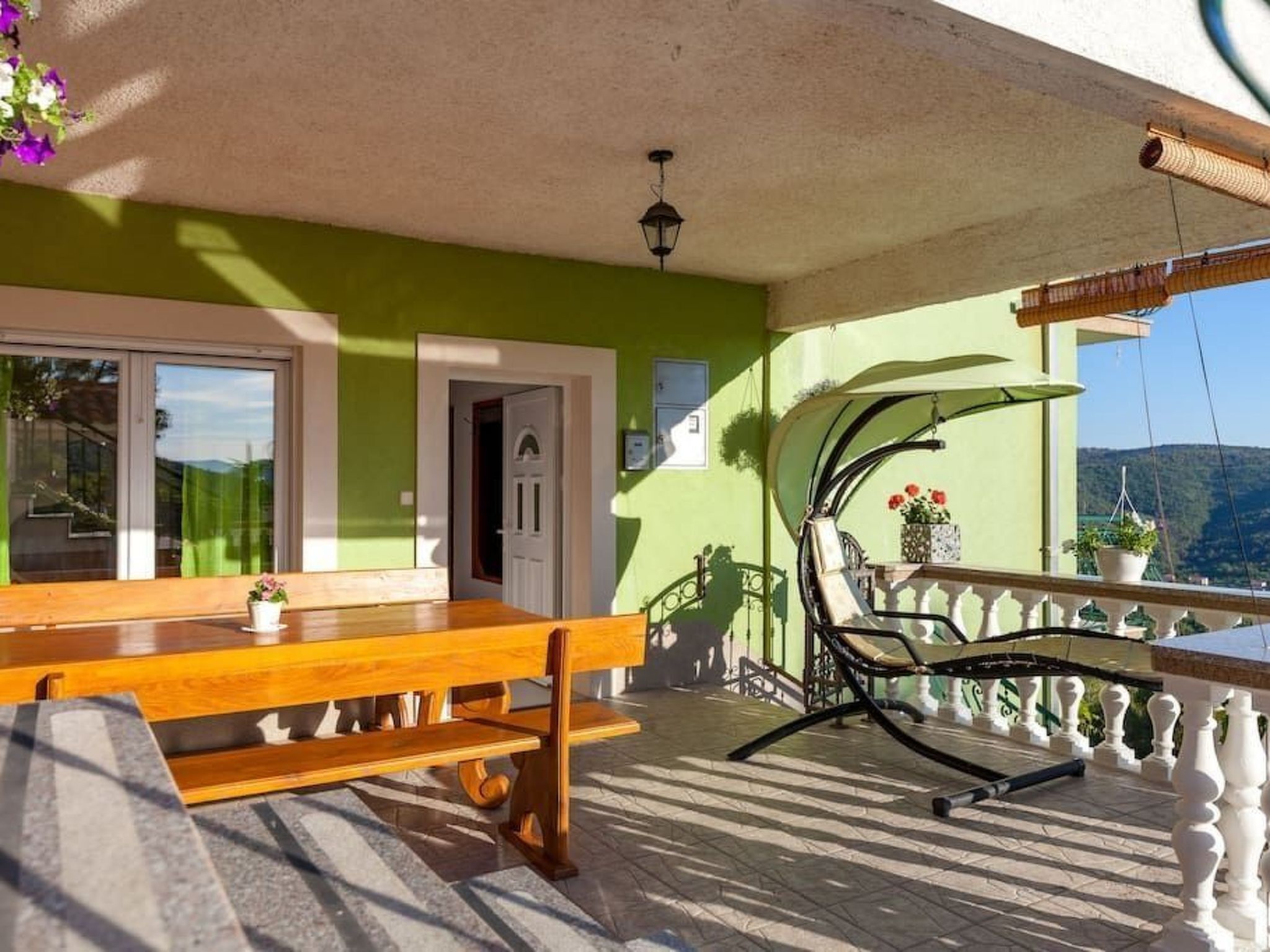 Eine Holzbank und ein Tisch auf einem Balkon mit Blick auf die Landschaft.