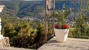 A balcony with a potted plant and a view of a village in the distance. - Privatwohnung mit Jacuzzi und Schwimmbad by Interhome (Split/Žrnovnica)